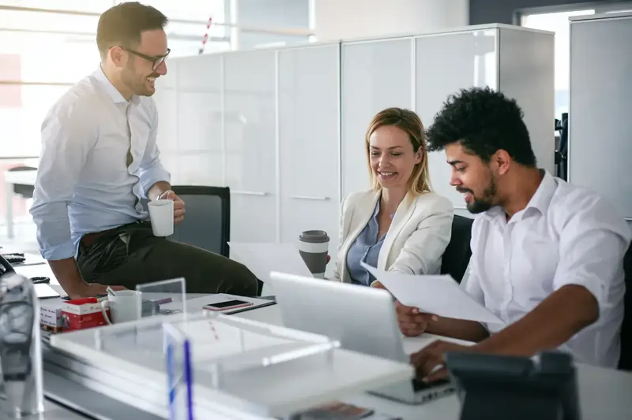 Team collaborating in an office while reviewing documents and working on a laptop.